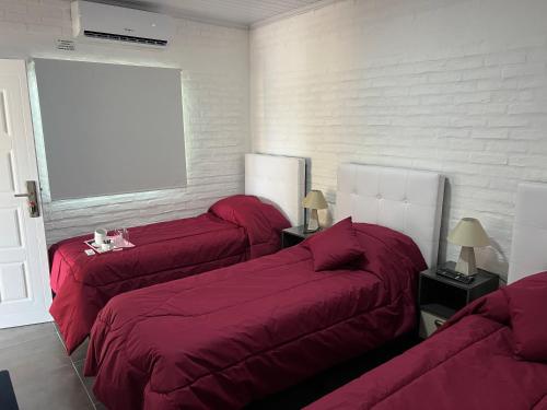 um quarto com 3 camas com lençóis vermelhos e uma janela em Apart del Este Loft 6 em Paysandú