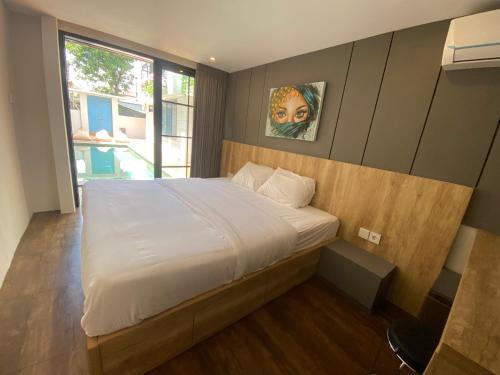 Un dormitorio con una cama blanca grande y una ventana en PAMELA BALI, en Kerobokan