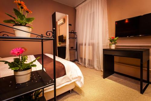 a hotel room with a bed and a desk with potted plants at Leo Hotel in Moscow