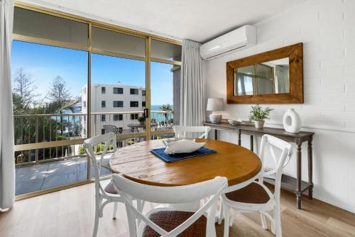 a dining room with a table and chairs and a balcony at Surf Dance Apartments in Coolum Beach