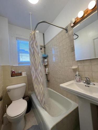 La salle de bains est pourvue de toilettes, d'une baignoire et d'un lavabo. dans l'établissement Private Room in a Grand House, à Boston