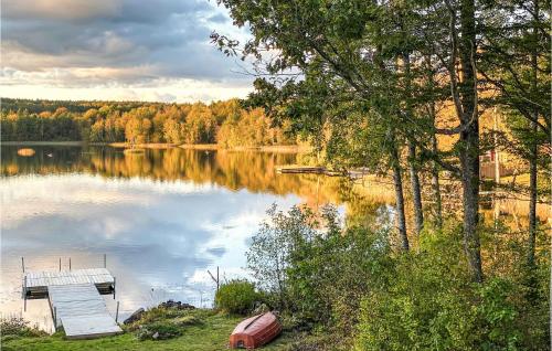 a lake with a dock and a boat on it at Cozy Home In Asarum With Lake View in Asarum