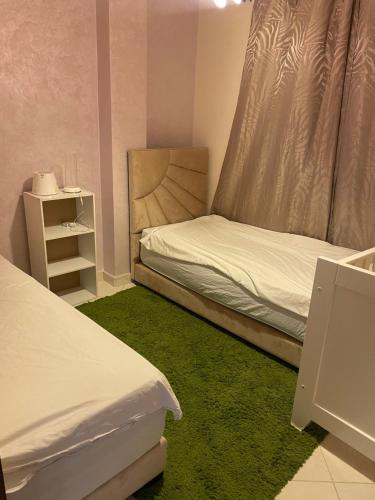 een kleine slaapkamer met 2 bedden en een groen tapijt bij Ryad zitoune in Meknès