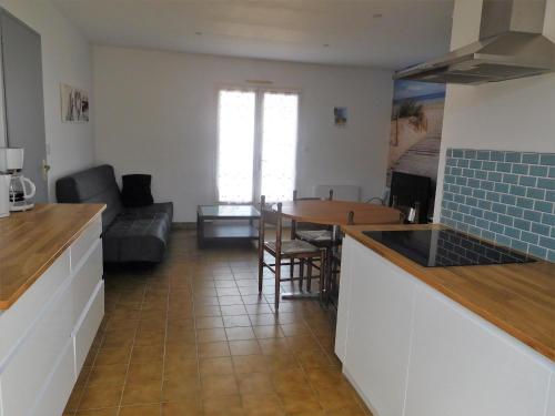 une cuisine et un salon avec une table et un canapé dans l'établissement Maison au calme avec jardin, proche plage et commerces, équipée pour famille de 6 personnes - FR-1-476-197, à La Faute-sur-Mer