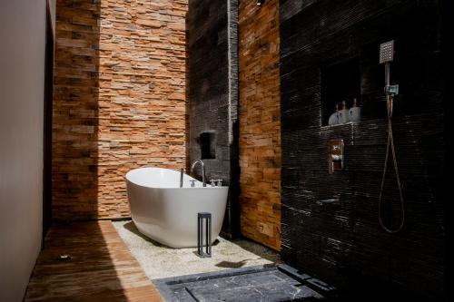 邦勞的住宿－Amphitrite Resort，浴室设有白色浴缸,毗邻砖墙