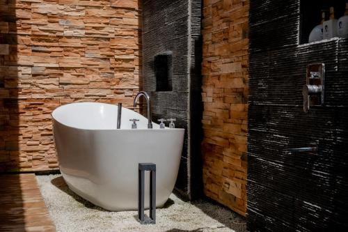 a large white tub in a bathroom with a brick wall at Amphitrite Resort in Panglao