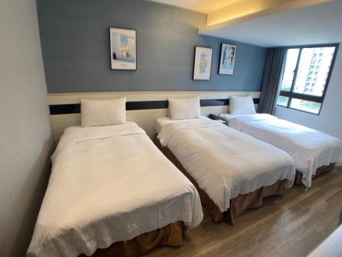 a room with three beds with white sheets at Taichung Saint Hotel in Taichung