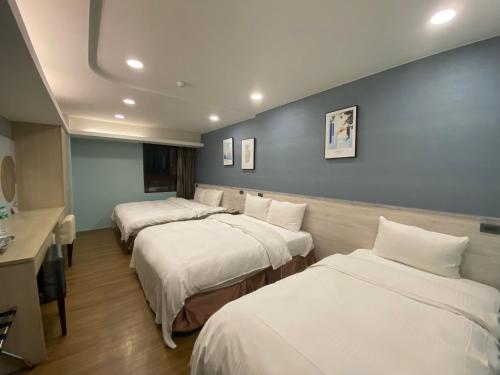 a hospital room with three beds and a desk at Taichung Saint Hotel in Taichung