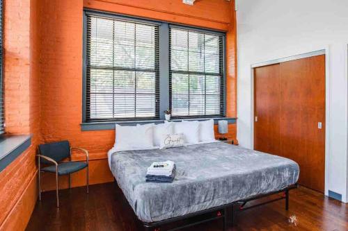 a bedroom with a bed and a chair and windows at NY Style Centric Loft with King Bed by Park av in Rochester