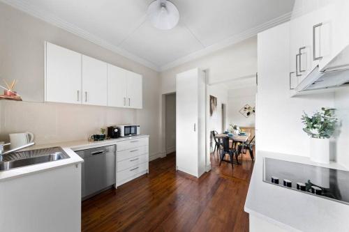 a kitchen with white cabinets and a wooden floor at Art Deco Hideaway - St Kilda in Melbourne