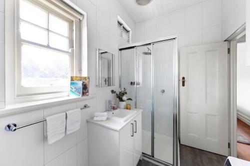 uma casa de banho branca com um lavatório e um chuveiro em Art Deco Hideaway - St Kilda em Melbourne