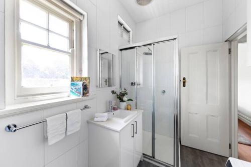 Un baño blanco con lavabo y ducha. en Art Deco Hideaway - St Kilda, en Melbourne
