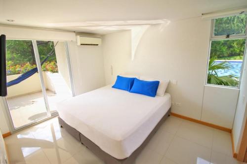 a white bed with blue pillows in a bedroom at Apartamento Santa Marta Bello Horizonte - Pozos Colorados in Santa Marta