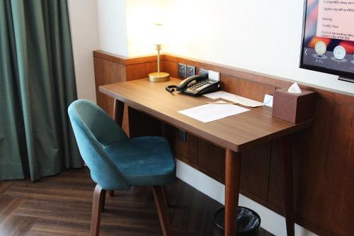 um quarto com uma secretária com uma cadeira e um telefone em WEIL Hotel Ipoh em Ipoh