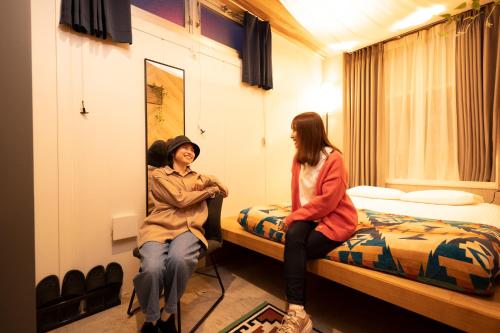 a man and a woman sitting on beds in a room at Glamping Tokyo Asakusa in Tokyo