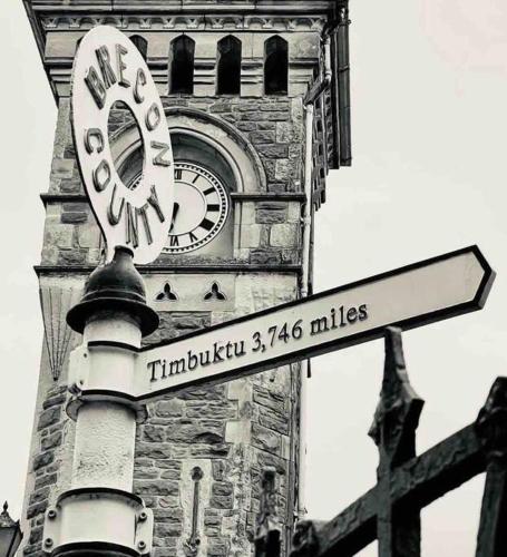 a clock tower with a street sign in front of it at Hay On Wye Welsh Townhouse in Hay centre in Hay-on-Wye