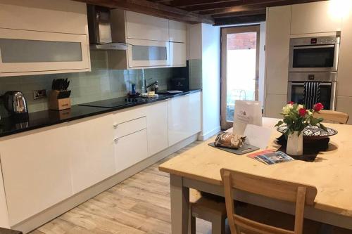 a kitchen with white cabinets and a wooden table at Hay On Wye Welsh Townhouse in Hay centre in Hay-on-Wye