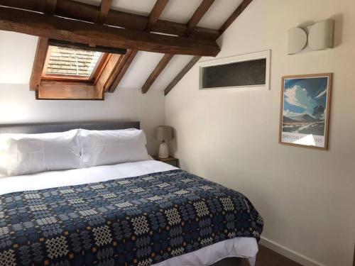 a bedroom with a bed with a blue blanket and a window at Hay On Wye Welsh Townhouse in Hay centre in Hay-on-Wye