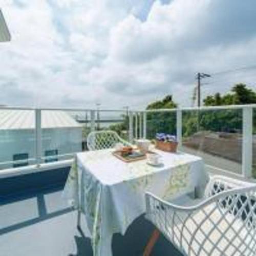 a balcony with a table and chairs on a balcony at Beachside base KURUWA in Yokosuka