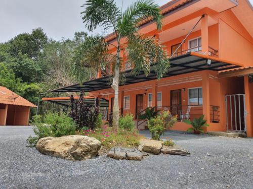 At Sichon Resort في سيتشون: منزل برتقالي مع نخلة وصخرة