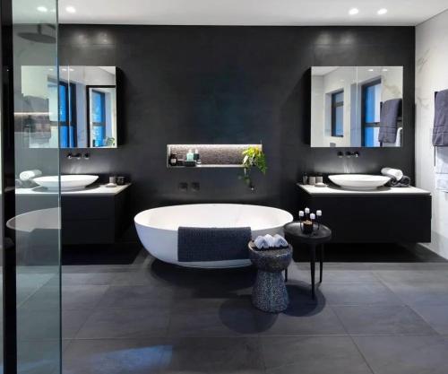 een badkamer met 2 wastafels, een bad en 2 spiegels bij 92 New road in Midrand