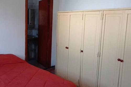 1 dormitorio con armarios blancos y 1 cama roja en Apto. en Colonia, a 1 cuadra de la Plaza de Toros, en Colonia del Sacramento