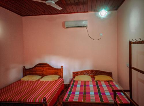 two beds in a room with pink walls at Sunny Lanka Guest House in Matara