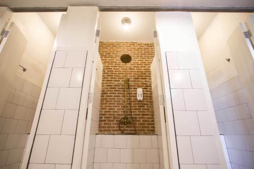 a bathroom with a shower with a brick wall at Here Hostel Bangkok in Bangkok