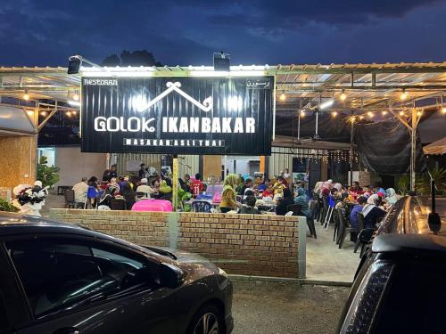 a crowd of people sitting at a restaurant at night at YB Guest House 4 Bilik 5 Katil in Cukai