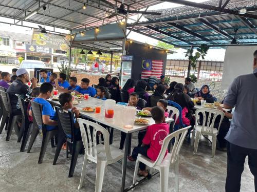 a group of children sitting at a table eating food at YB Guest House 4 Bilik 5 Katil in Cukai