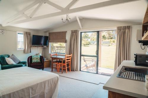 a hotel room with a bed and a kitchen with a table at The Hen House in Kaipara Flats