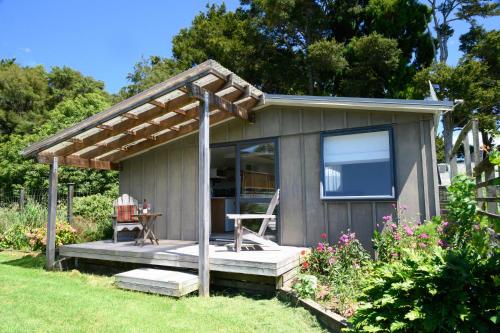 a small shed with a table and a chair in a yard at The Hen House in Kaipara Flats