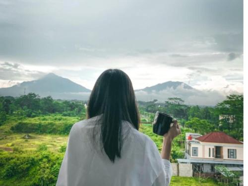 a woman taking a picture of the mountains at Front One The Andia Boyolali in Boyolali