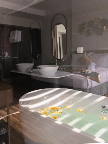 a bathroom with two sinks and a tub with flowers in it at Grand Tourane Nha Trang Hotel in Nha Trang