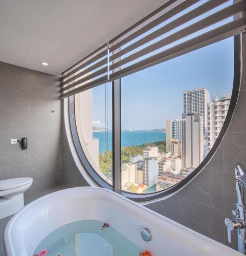 a bathroom with a tub and a large window at Grand Tourane Nha Trang Hotel in Nha Trang