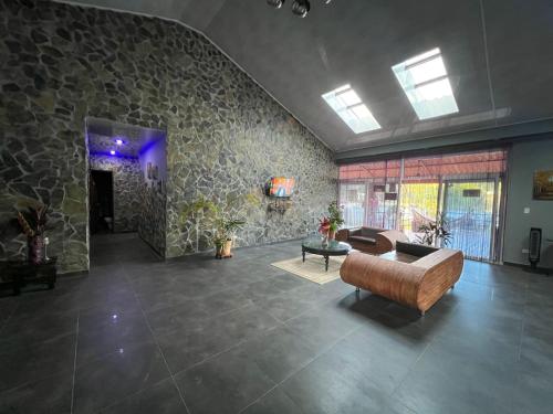 a living room with a couch and a stone wall at Cabañas Lago Cerro Azul - Lake of Panama in Cerro Azul