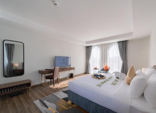 a hotel room with a large white bed and a desk at Grand Tourane Nha Trang Hotel in Nha Trang