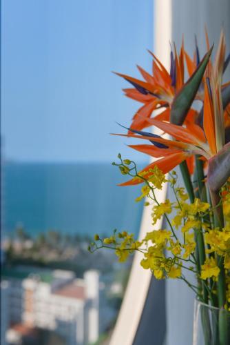 a vase of flowers with a view of the city at Grand Tourane Nha Trang Hotel in Nha Trang