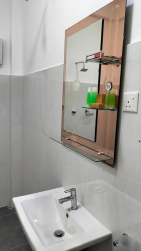 une salle de bain avec un lavabo et un miroir dans l'établissement Hotel Sun Blue, à Trincomalee