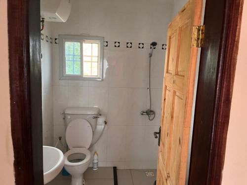 a bathroom with a toilet and a sink and a window at B&Y Holiday Apartments in Brusubi