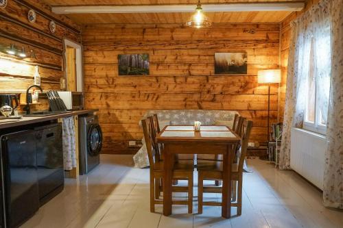 - une table et des chaises dans une cuisine avec des murs en bois dans l'établissement Karolówka Nad Osławą, à Czaszyn