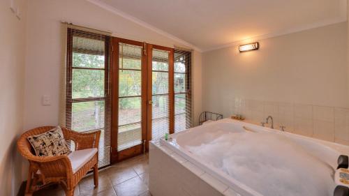 a large white bath tub in a room with windows at Beechworth Cedar Cottages in Beechworth