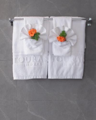 two white towels with orange flowers on them at Grand Tourane Nha Trang Hotel in Nha Trang
