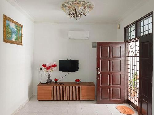 een woonkamer met een tv en een deur met een tafel bij HELLO HOMESTAY in Nibung Tebal