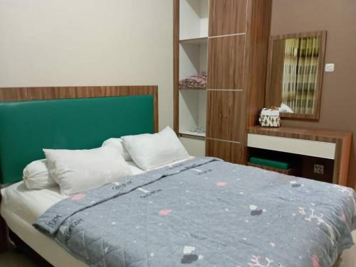 a bedroom with a bed with a green headboard at SpringHills Villa Panderman Batu - Private Pool in Tlekung