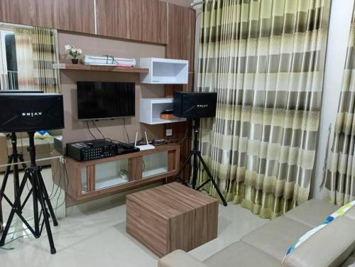 a living room with a television and a desk with a monitor at SpringHills Villa Panderman Batu - Private Pool in Tlekung