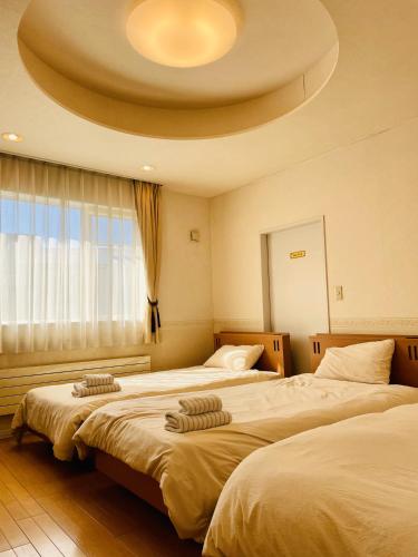 two beds in a hotel room with a circular ceiling at ユーカラ屋 in Nanae