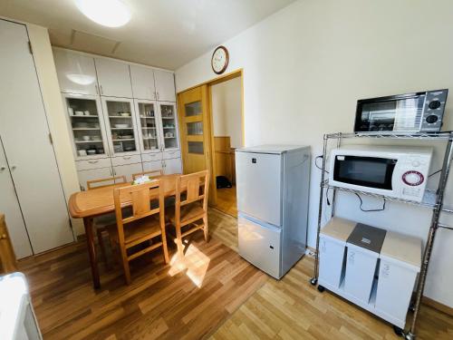 uma cozinha com uma mesa, um micro-ondas e um frigorífico em 民泊なべやさんち em Nanae