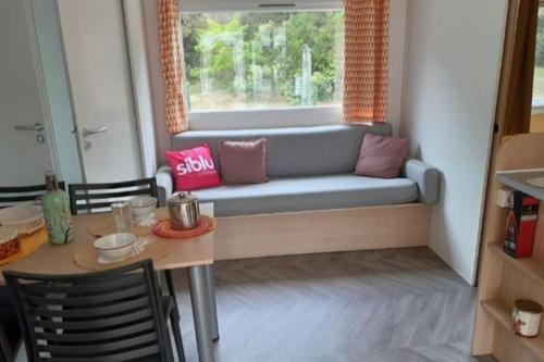 ein Wohnzimmer mit einem Sofa vor einem Fenster in der Unterkunft Mobilhome 4 pers La palmyre in Les Mathes