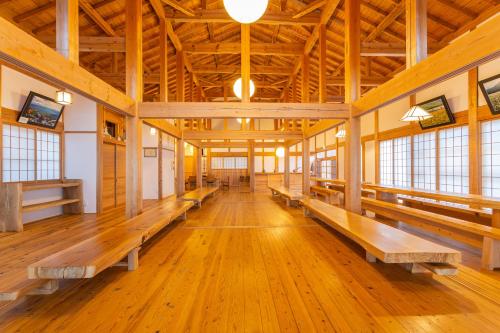 Una gran sala con bancos de madera en un edificio. en 響きの宿, en Sato-moriya